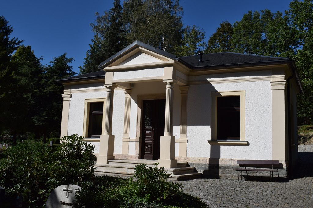 Außenansicht der Totenhalle in Dittersdorf mit Säulenportal vor Bäumen 